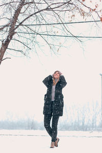 Full length of woman on snow covered tree