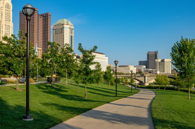 Trees and buildings against clear blue sky