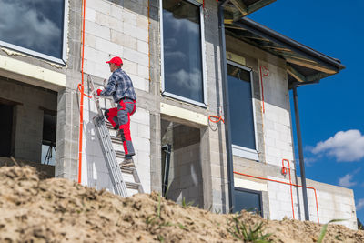 Low angle view of man standing by building against sky