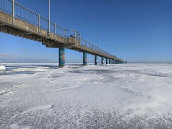 Bridge over sea against clear blue sky