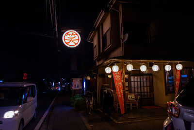 Illuminated road sign on street amidst buildings in city at night