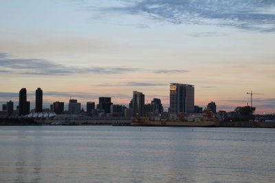 Sea with city in background at sunset