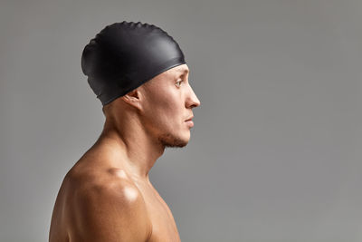 Side view of man wearing swimming cap against gray background