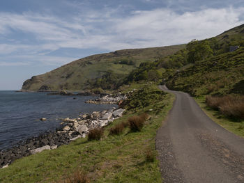 Scenic view of road by sea against sky