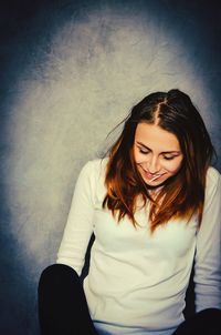 Smiling young woman against wall