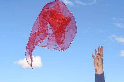 Low angle view of hand against blue sky