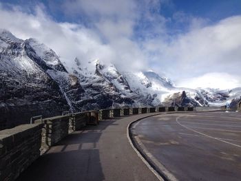 Road by mountains against sky during winter