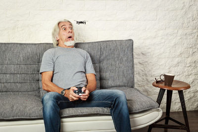 Full length of man sitting on sofa at home