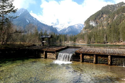 Scenic view of dam and mountains against sky