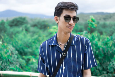 Young man wearing sunglasses against trees