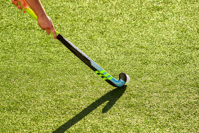 Cropped image of player playing hockey on field during sunny day