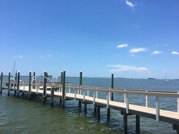 Wooden posts in sea against blue sky