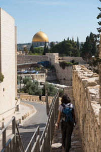 Rear view of woman with backpack walking in alley