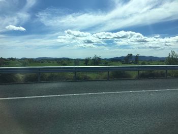 Road by trees against sky