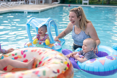 Mother with children on inflatable rings in swimming pool