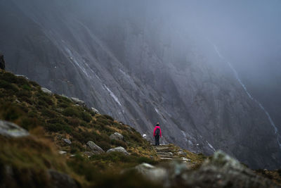 Rear view of person standing on rock against mountains