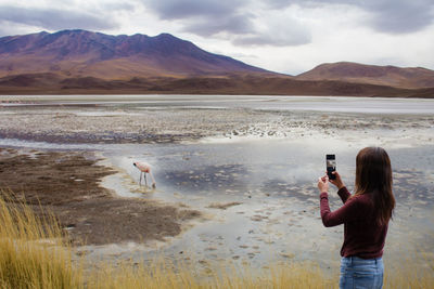 Man photographing sea against mountains