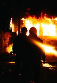 Rear view of silhouette people against fire crackers at night