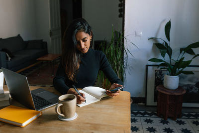 Young woman using mobile phone at home