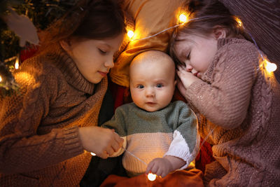 Funny children sleep together and embrace in a dark cozy interior, in warm sweaters 