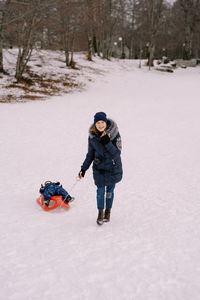 Rear view of woman skiing on snow covered field