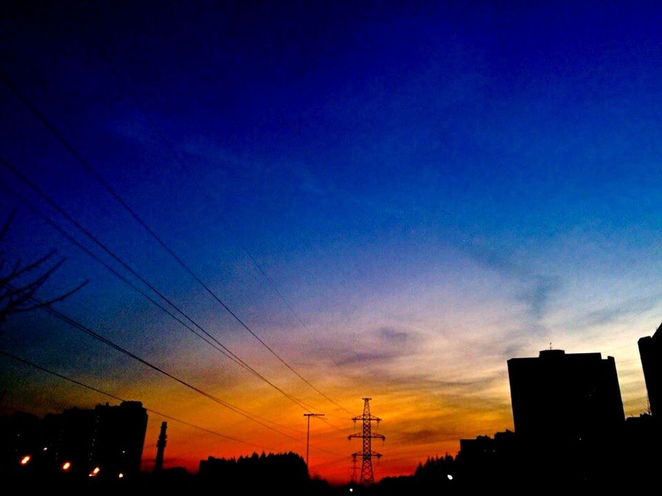 silhouette, sunset, power line, low angle view, sky, building exterior, electricity pylon, built structure, architecture, electricity, cable, power supply, connection, dusk, blue, city, cloud - sky, orange color, cloud, outdoors