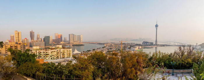 Panoramic shot of city by sea against clear sky