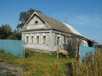 Cottage house on field against sky