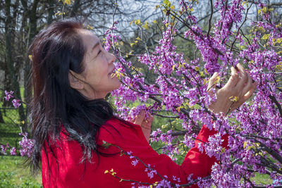 Close-up of woman with pink flowers against trees