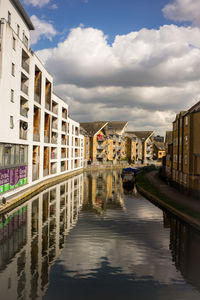 Canal amidst buildings in city against sky