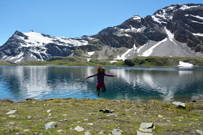 Rear view of woman jumping against lake