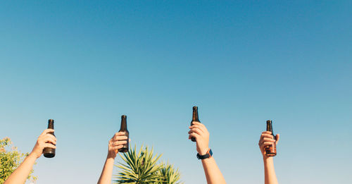 Closeup shot of bottles lifted high on blue sky background
