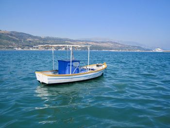 Boat sailing in sea against clear blue sky