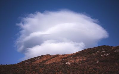 White fluffy cloud above highland landscape