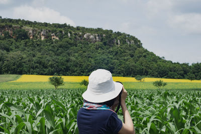 Woman wearing hat photographing against mountains