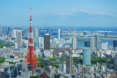 Tokyo tower amidst buildings against sky on sunny day