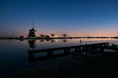 Windmill and pier along river rotte in holland during blue hour
