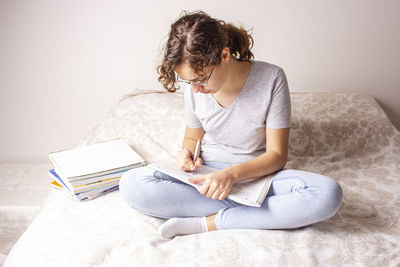 Woman sitting on book at home