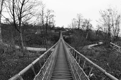 High angle view of footbridge amidst bare trees on field