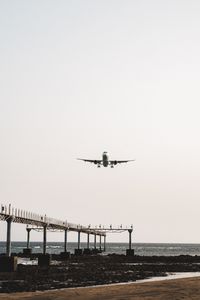 Airplane flying over sea against clear sky