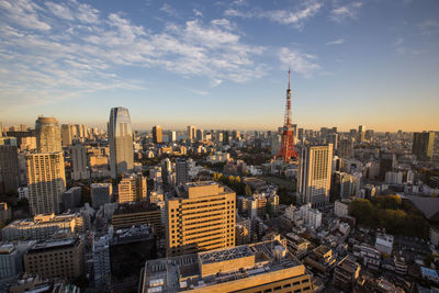 Tokyo tower amidst buildings in city against sky during sunset