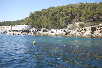 Scenic view of sea by buildings against clear sky