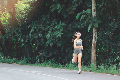 Full length of woman on road against trees