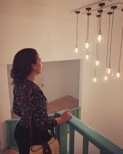 Side view of woman standing against wall at home