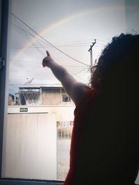 Man holding glass window against sky