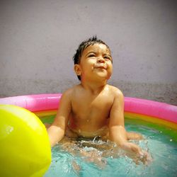 Shirtless baby girl enjoying in wading pool at back yard