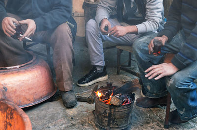 Low section of people sitting on floor in front of fire 