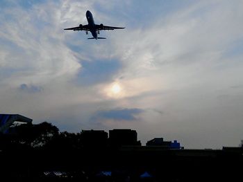 Low angle view of airplane flying against cloudy sky