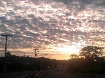 Cars on road against sky during sunset