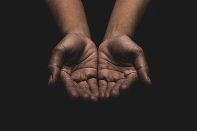 Close-up of hands cupped over black background